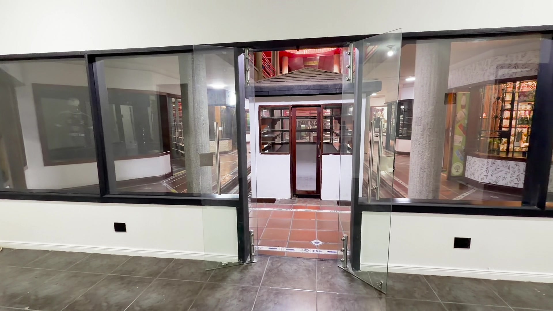 Interior del local hacia la vitrina, con la puerta de vidrio abierta
